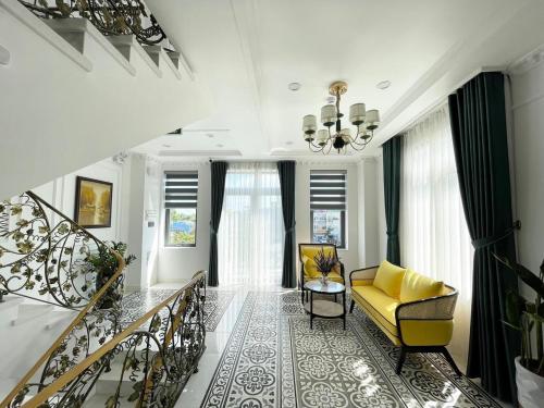 a living room with a yellow chair and stairs at Paris Hotel & Cafe in Vĩnh Long
