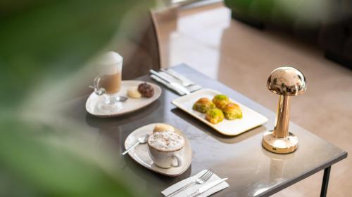 a table with two plates of food and a cup of coffee at Crown Salamis Hotel in Mağusa