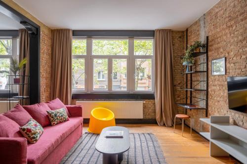 a living room with a pink couch and a brick wall at Smartflats - the Brooklyn Antwerp in Antwerp