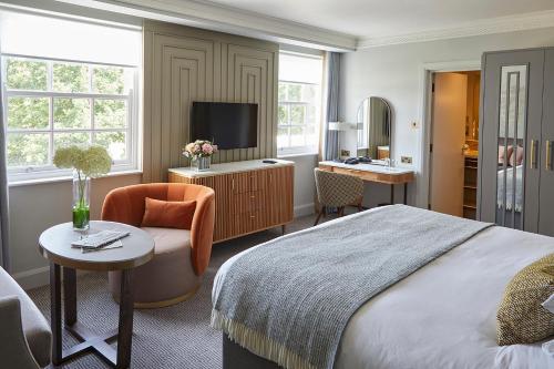 a bedroom with a bed and a chair and a tv at Sopwell House Hotel in Saint Albans