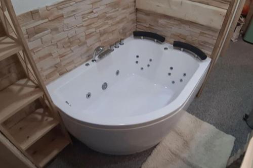 uma banheira branca num quarto com uma parede de tijolos em Chalet Luna em Klippitztorl