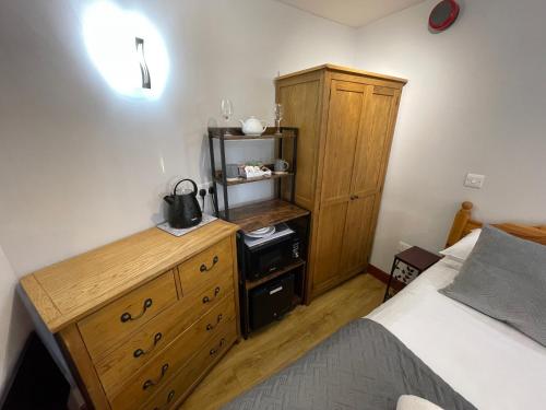 a bedroom with a bed and a wooden dresser at Quaysiders Lakes Resort - Quaysiders Club in Ambleside