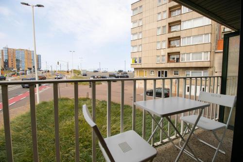 a balcony with a table and chairs and a street at Zeebries Studio in Ostend