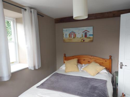 1 Schlafzimmer mit einem Bett mit einem Kopfteil aus Holz und 2 Kissen in der Unterkunft Daisy Cottage in Child Okeford