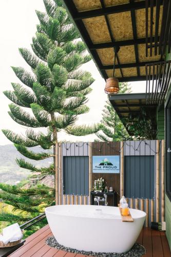 a bath tub sitting on a deck next to a palm tree at The Proud Resort @Khao kho in Khao Kho
