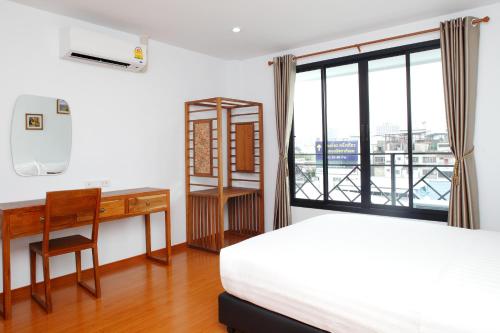 a bedroom with a bed and a desk and a window at Double DD House at MRT Sutthisarn in Bangkok