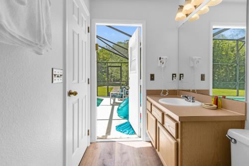 a bathroom with a sink and a door leading to a patio at 1061 Lake Berkley 4 Bed with Pool&Spa in Kissimmee