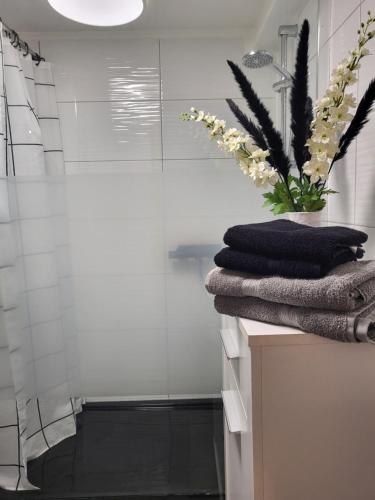 uma casa de banho com um chuveiro, toalhas e um vaso de flores em Zum goldenen Hirsch am Paulaner em Höxter
