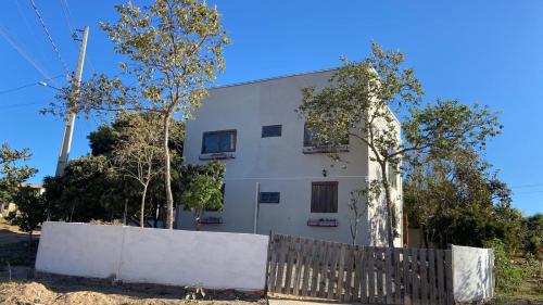 uma casa branca com uma cerca à frente. em Casa em Alto Paraíso com vista para as montanhas no Eldorado ao lado do centro em Alto Paraíso de Goiás