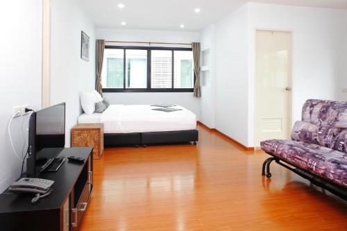 a bedroom with a bed and a tv and a couch at Double DD House at MRT Sutthisarn in Bangkok