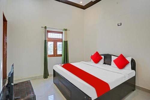 sypialnia z łóżkiem z czerwonymi poduszkami i telewizorem w obiekcie OYO Flagship Hotel Midtown 2 w mieście Noida
