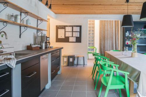 a kitchen with a counter and green chairs in it at Villa Verde Österlen in Glemminge