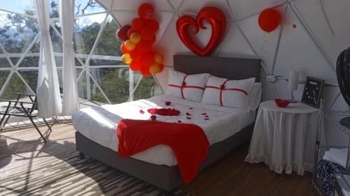 a bedroom with a bed with red and orange balloons at Glamping Campestre Uriyahu in Macanal