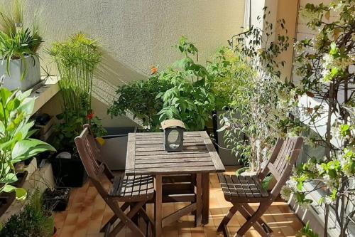 une terrasse avec une table en bois, des chaises et des plantes dans l'établissement Le Monspetellarius (parking, terrasse & clim), à Montpellier