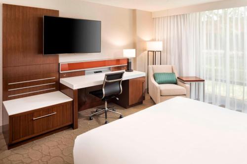 a hotel room with a bed and a desk and a tv at Delta Hotels by Marriott Minneapolis Northeast in Minneapolis