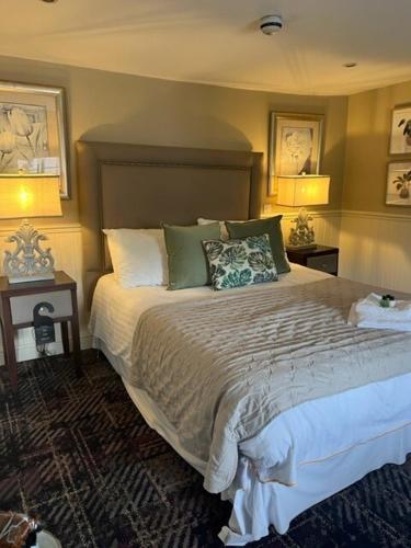 a bedroom with a large bed with two tables and two lamps at The New Boar in Theydon Bois