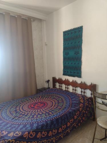 ein Schlafzimmer mit einem Bett mit einer farbenfrohen Tagesdecke in der Unterkunft Loft encantador centro Guarapari in Guarapari