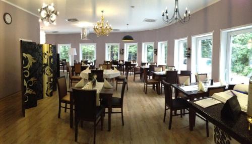 - une salle à manger avec des tables, des chaises et des fenêtres dans l'établissement Hotel Haus Hubertus, à Schneverdingen