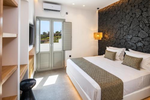 a bedroom with a bed with a stone wall at Anatelo house in Fira