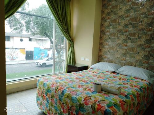 een slaapkamer met een bed en een groot raam bij HOSPEDAJE YACUCALLE in Ibarra