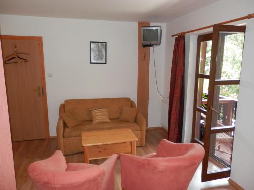 un salon avec un canapé et deux chaises roses dans l'établissement Penzion Stárek, à Terchová