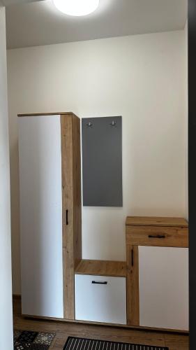 a room with a white wall with a cabinet and a table at Japandi apartamentai in Kaunas