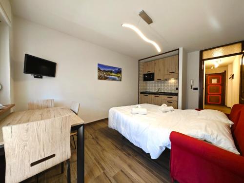 - une chambre avec un grand lit blanc et une chaise rouge dans l'établissement Hostdomus - City Center Apartment, à Sestrières