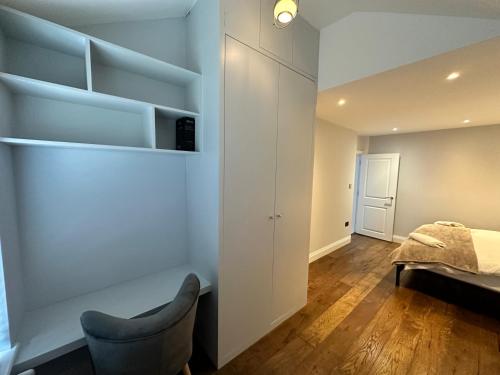 a bedroom with a bed and a chair in a room at A super luxury large apartment in Barnet