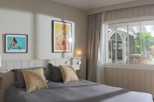 um quarto com uma cama com almofadas e uma janela em La villa aux oiseaux em Andernos-les-Bains