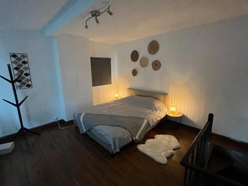 a bedroom with a bed and two lights on the wall at Charmante petite maison à Olne in Olne