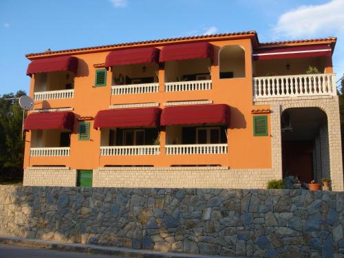 een gebouw met rode luifels op een stenen muur bij Villa Delina in Rab