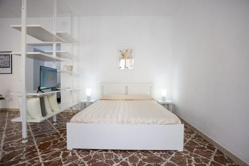 a white bedroom with a bed and a tv at Al 26 Apartment in Erice
