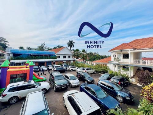 a parking lot with cars parked in front of a hotel at Infinity Hotel Kampala in Kampala