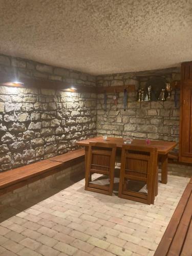 een stenen kamer met een houten tafel en banken bij FÜGÉSKERT in Balatonfüred