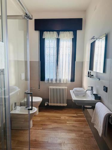 a bathroom with two sinks and a toilet and a window at Hotel Banatium B&B Cucina in Tezze sul Brenta