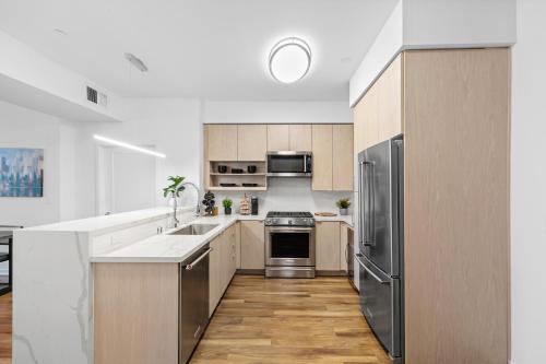 una cocina con electrodomésticos de acero inoxidable y armarios de madera en Beverly Grove Chic City Oasis 2 BR Apt with Den 138, en Los Ángeles