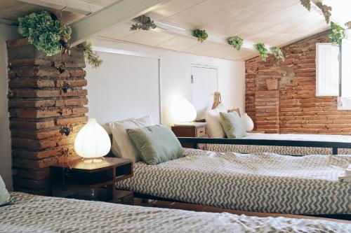 sypialnia z 2 łóżkami i ceglaną ścianą w obiekcie Casa Pereirinha \ Pateo House w mieście Vidigueira