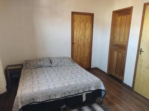 una camera con un letto e due porte in legno di Apartamento Bela Vista a Tiradentes
