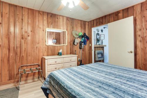 a bedroom with wooden walls and a bed and a dresser at Dog-Friendly Kingston Cabin with Wraparound Deck! in Kingston