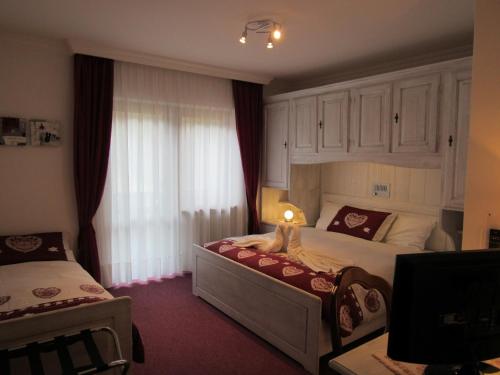 a bedroom with two beds and a large window at Park Hotel Arnica in Falcade