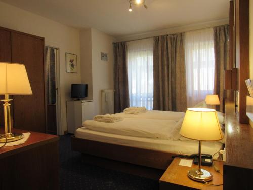 une chambre d'hôtel avec un lit et deux lampes dans l'établissement Park Hotel Arnica, à Falcade