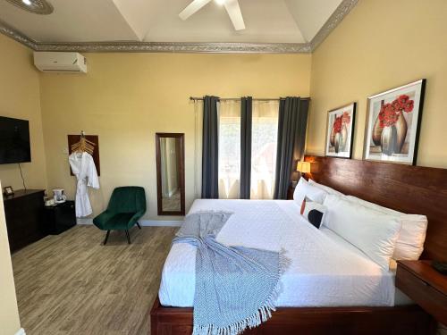 a bedroom with a large bed and a green chair at Villa Panorama in Montego Bay