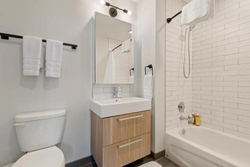 a bathroom with a toilet and a sink and a tub at Experience Downtown Chicago at Millennium - Luxury Apartments in The Loop in Chicago