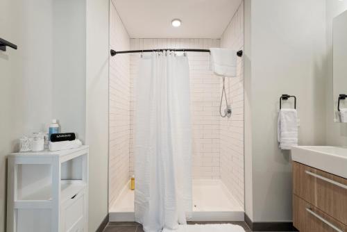 a bathroom with a shower with a white shower curtain at Experience Downtown Chicago at Millennium - Luxury Apartments in The Loop in Chicago