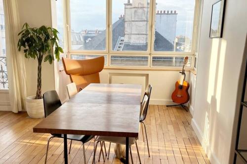 uma mesa e cadeiras numa sala com uma guitarra em Appartement au pied de Montmartre / Jules Joffrin em Paris