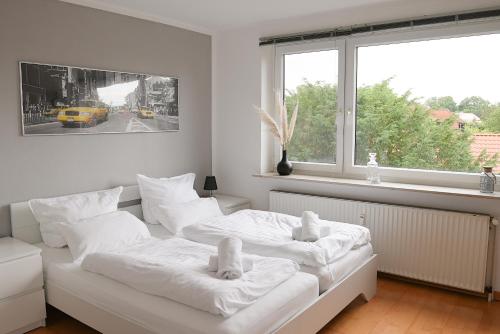 2 camas en una habitación blanca con ventana en Remark Studios - Wohnung für 6 in Großburgwedel, en Burgwedel