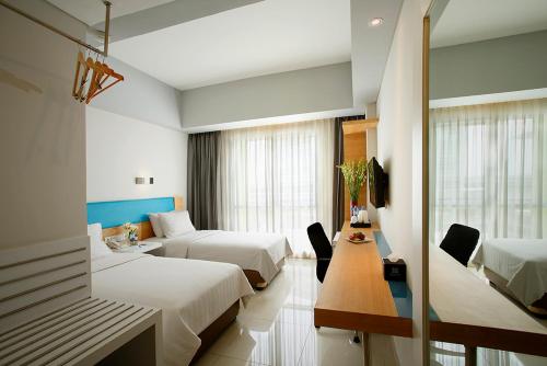 Habitación de hotel con 2 camas y mesa en BATIQA Hotel & Apartments Karawang, en Karawang