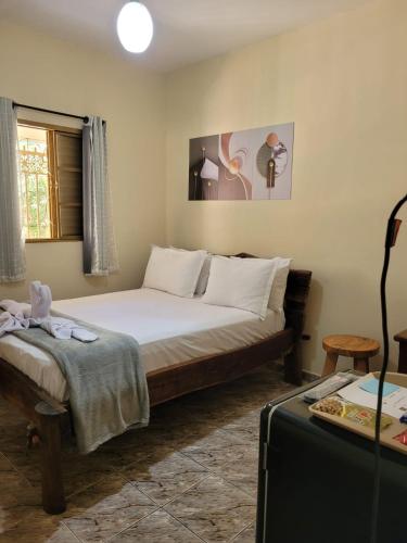 a bedroom with a bed and a table with a suitcase at Suítes Boa Viagem in Pirenópolis