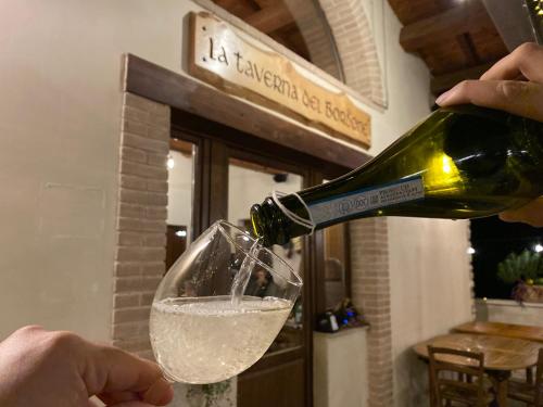 a person pouring a bottle of wine into a glass at Il Tripode - Le Dimore del Bordone in Vallo di Nera