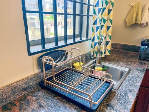 a kitchen sink with a dish drying rack next to a window at Cozy & tranquil 1 Bedroom dainty haven in Kampala in Buwate